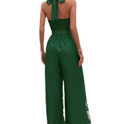 Backless halter jumpsuit in green, featuring a high waist and flowing trousers.