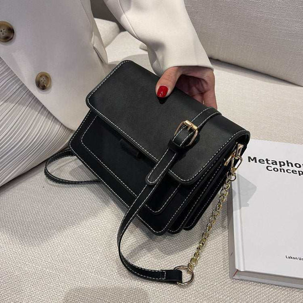 Square Chain Shoulder Bag with chain strap on table near book.
