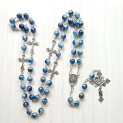 Rosary necklace with blue beads and cross pendant on a light background.