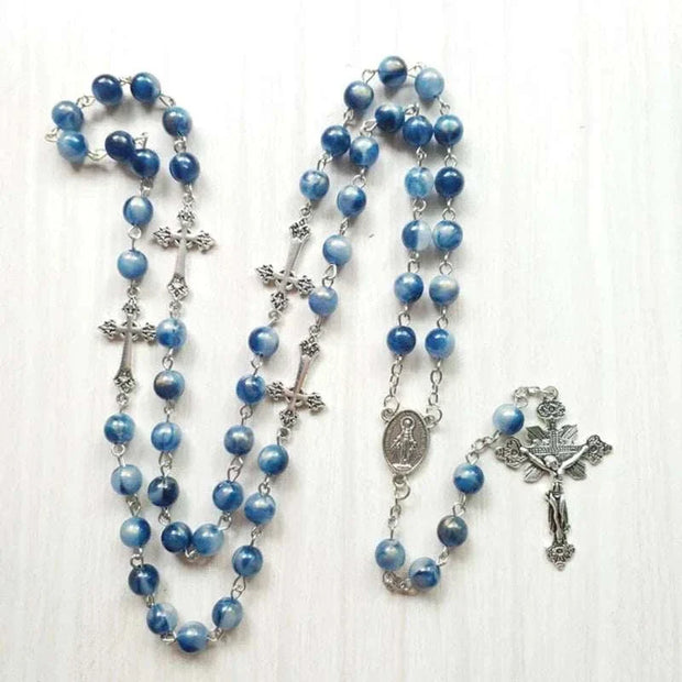 Rosary necklace with blue beads and cross pendant on a light background.