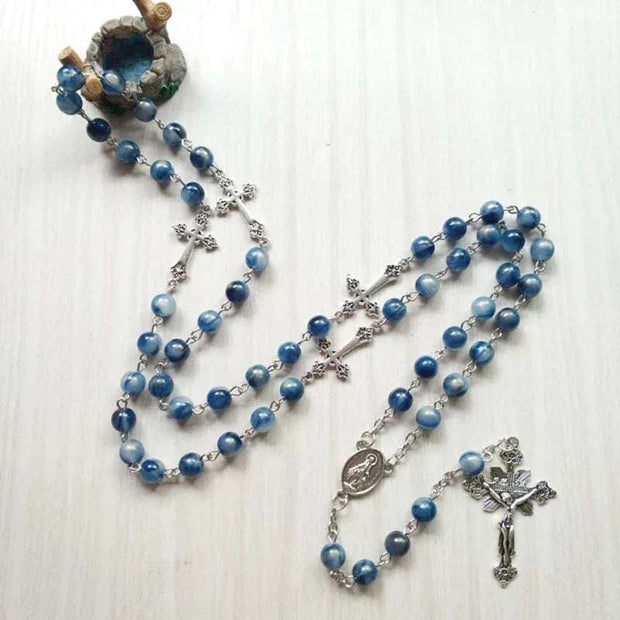 Rosary necklace with cross pendant featuring blue beads, symbolizing spirituality and faith.