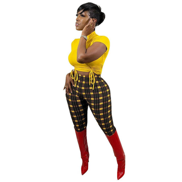 Casual silk print leggings with plaid design in black and yellow, paired with a yellow top and red boots.