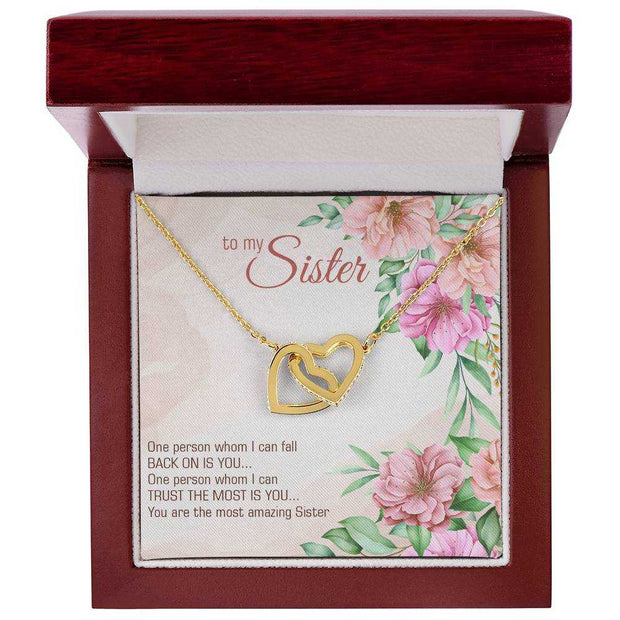 Interlocking Heart Necklace in gift box with floral background, symbolizing hope and positivity.