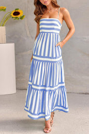 Green striped smocked dress with spaghetti straps and flowing tiered skirt against a neutral background.