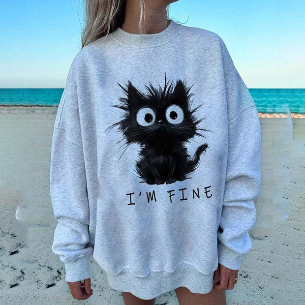 Woman wearing gray kitten graphic sweatshirt with "I'm Fine" text on beach
