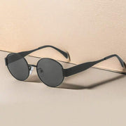 Metal Oval Vintage Sunglasses with black frames on beige background.
