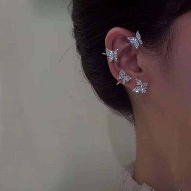 Butterfly ear clip earrings with elegant design, silver color, worn on person.