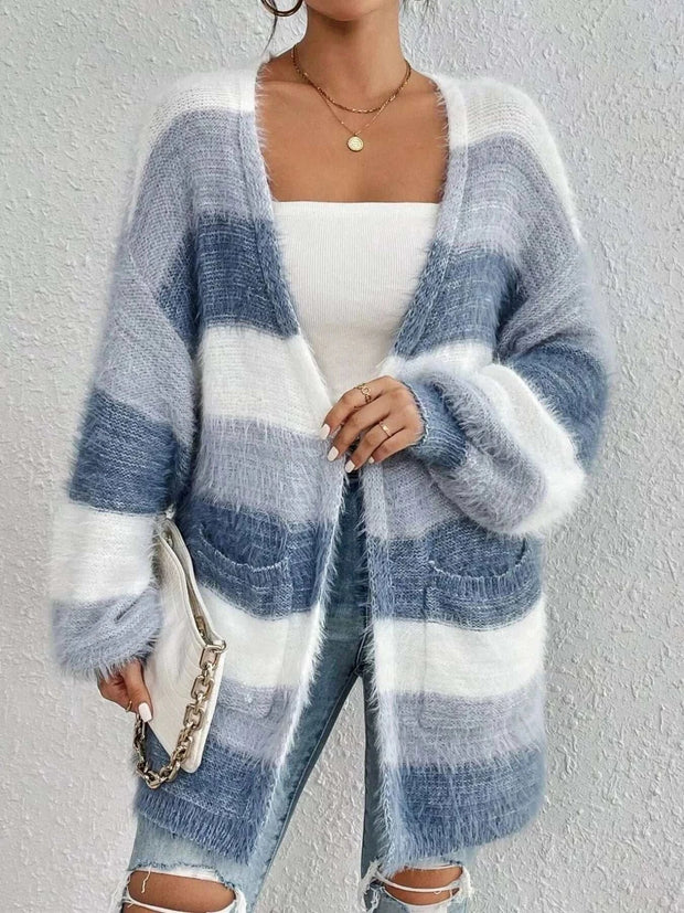 Woman wearing open front striped knit cardigan with wide horizontal blue and white stripes, paired with white top and ripped jeans