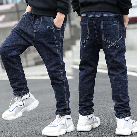 Boys wearing dark wash denim jeans and white sneakers, showcasing front and back views with hands in pockets, highlighting the jeans' comfortable and stylish fit.