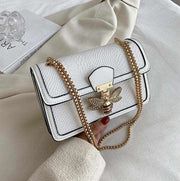 Chain Shoulder Bag with gold chain strap and stylish clasp on white fabric background.