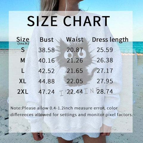 Size chart for Kitten Graphic Sweatshirt with bust, waist, and dress length measurements on a white sweatshirt featuring a playful black kitten graphic, worn by a person on a beach background