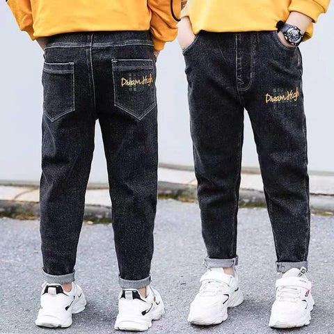 Boys wearing stylish black denim jeans with yellow sweatshirt and sneakers.