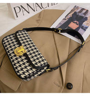 Houndstooth Baguette Bag with classic pattern on beige jacket.