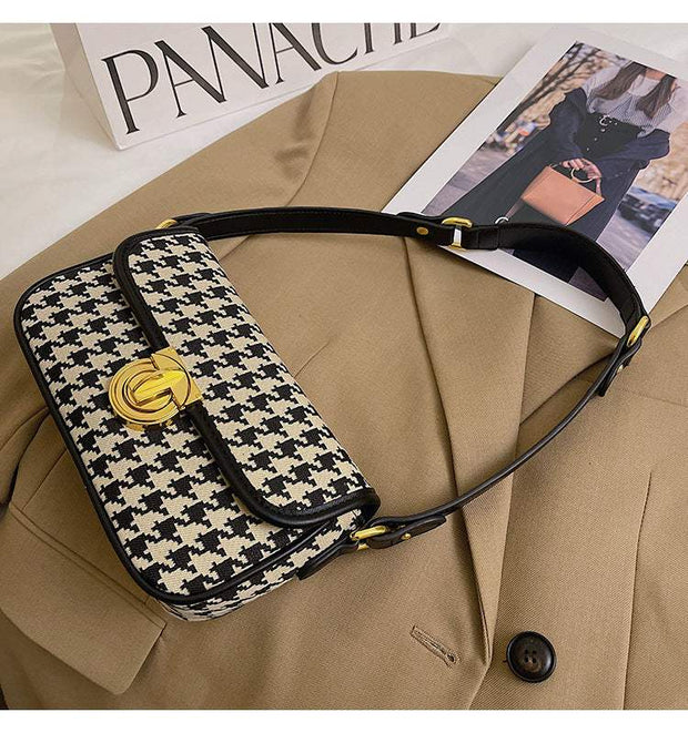 Houndstooth Baguette Bag with classic pattern on beige jacket.