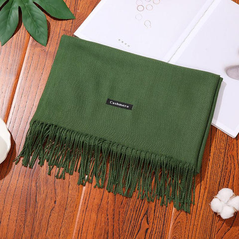 Green designer scarf shawl with tassels on a wooden surface, featuring a cashmere label.