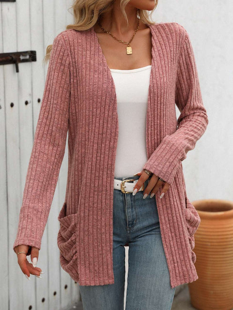 Woman wearing a pink open-front ribbed cardigan over a white top and jeans, showcasing casual style.