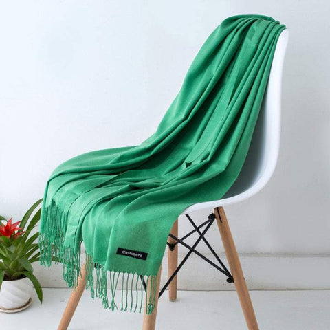 Elegant green designer scarf shawl draped over a white chair, showcasing its luxurious, high-quality fabric and chic contemporary style.