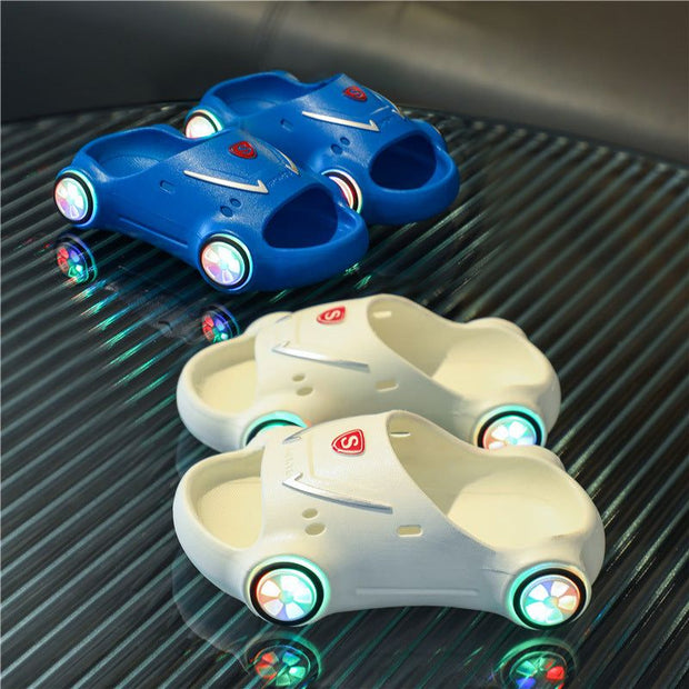 Kids Glowing Slippers with LED lights and car design on transparent surface.