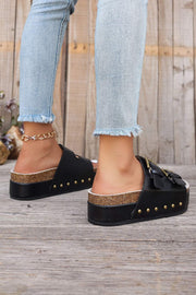 Chestnut Studded Platform Slides with chic black design and bold studs, featuring a dual buckle on model wearing jeans.