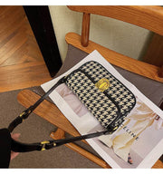 Houndstooth Baguette Bag with classic pattern on a wooden chair.