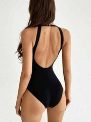 Woman wearing a black mesh backless swimsuit showing the open back design
