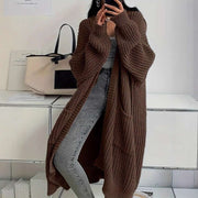woman wearing brown long sleeve long knitted cardigan with pockets and gray jeans indoors stylish outfit
