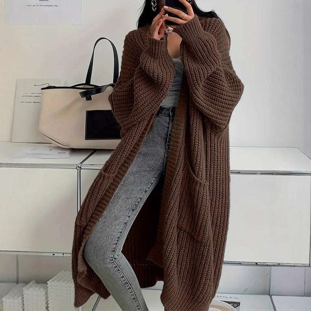 woman wearing brown long sleeve long knitted cardigan with pockets and gray jeans indoors stylish outfit