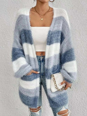 Woman wearing open front striped knit cardigan with gray and white horizontal stripes, paired with white crop top and ripped jeans