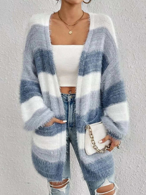 Woman wearing open front striped knit cardigan with gray and white horizontal stripes, paired with white crop top and ripped jeans