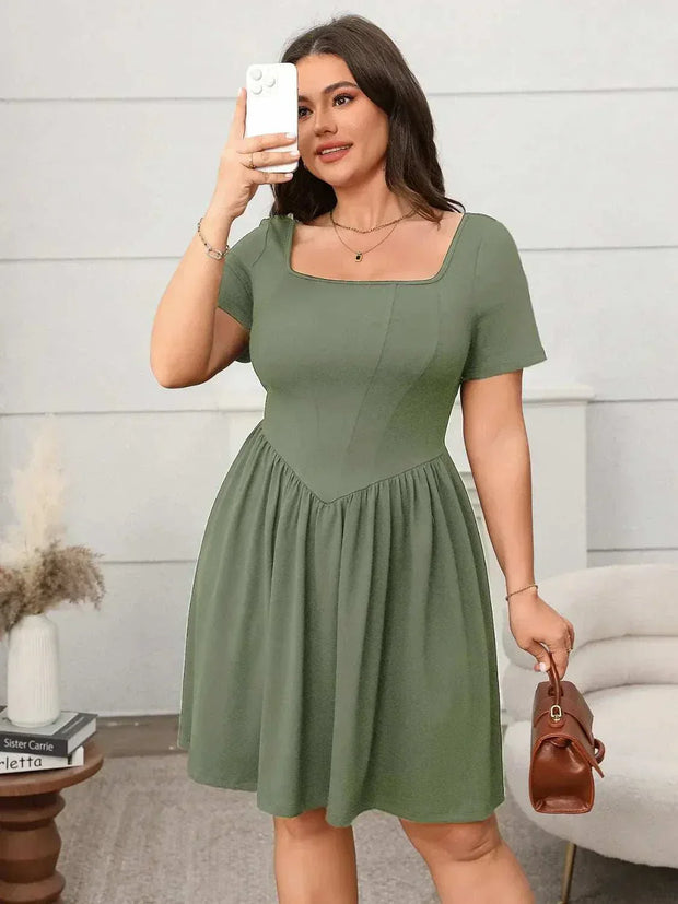 Plus size square-neck short-sleeve mini dress in green on a woman taking a selfie, showcasing the dress's flattering fit and modern design.