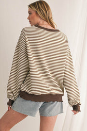 Woman wearing a casual striped drop shoulder top with long sleeves, paired with denim shorts.