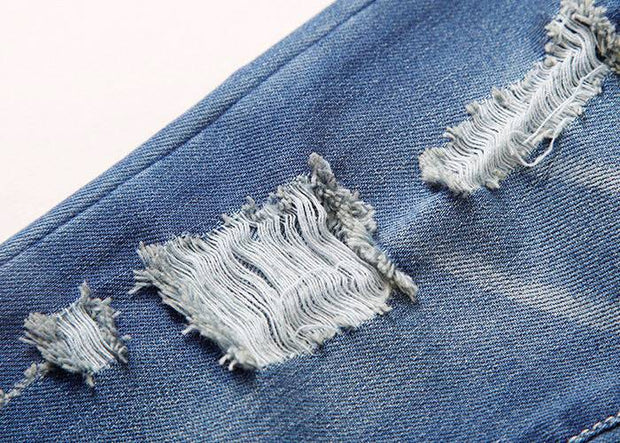 Close-up of European style boys ripped jeans showcasing distressed denim details.