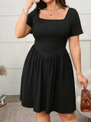 Plus size square-neck short-sleeve black mini dress with a fitted bodice and flowing skirt.