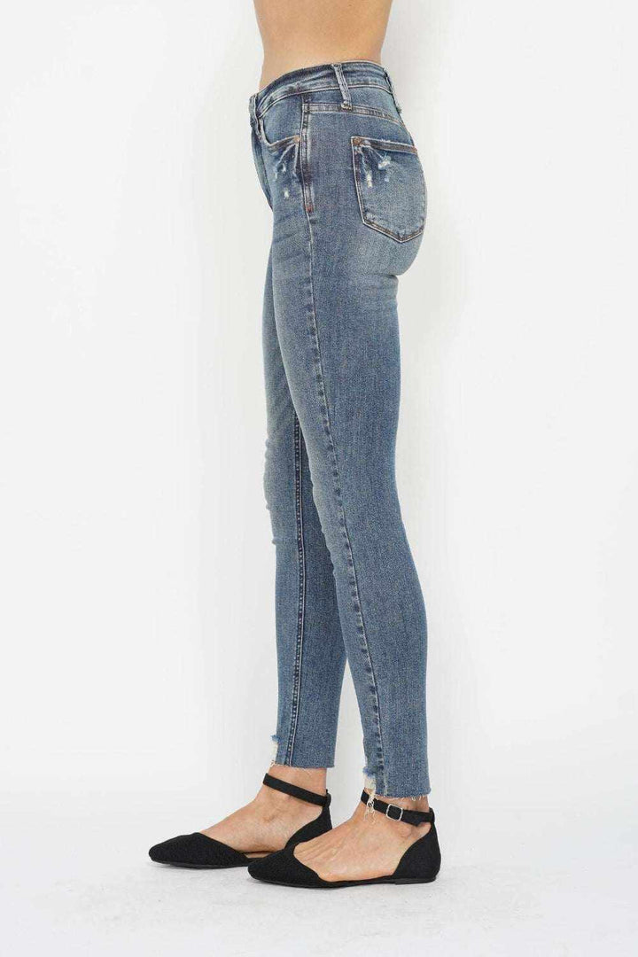 Woman wearing Judy Blue Tummy Control Skinny Jeans in vintage wash with distressed hem and tummy-control waistband