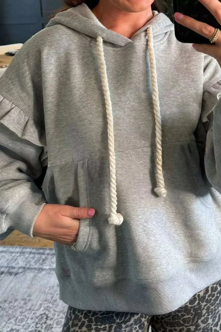 Woman wearing SYNZ Ruffled Hoodie with feminine ruffle details and adjustable drawstring hood