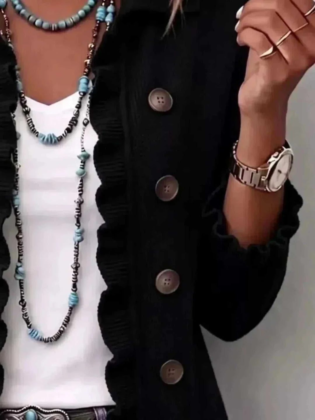 Women’s Plus Size Ruffled Cardigan in black knit with ruffled edging and large brown buttons, worn over a white top