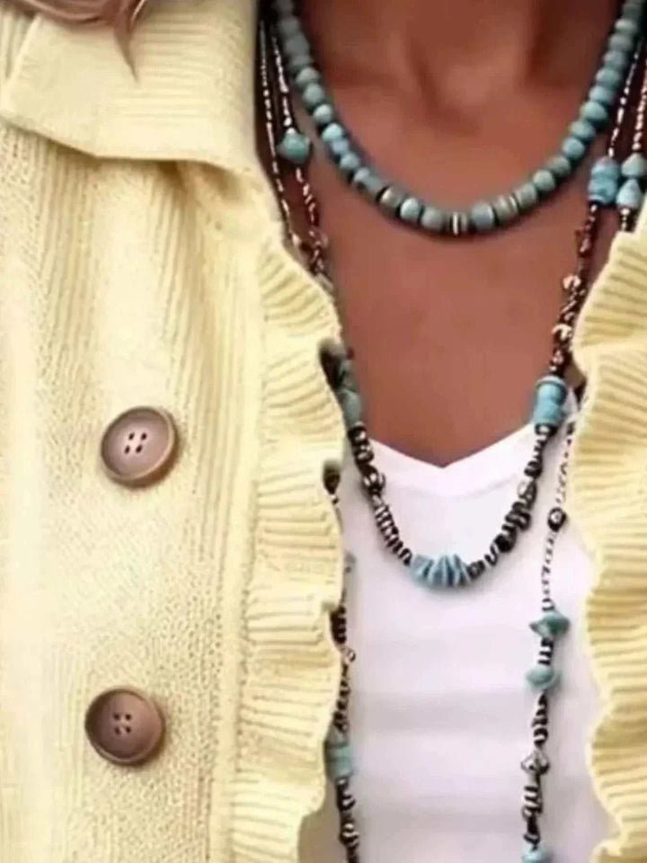 Women’s Plus Size Ruffled Cardigan in pale yellow knit with brown buttons and ruffled edges, layered over a white top