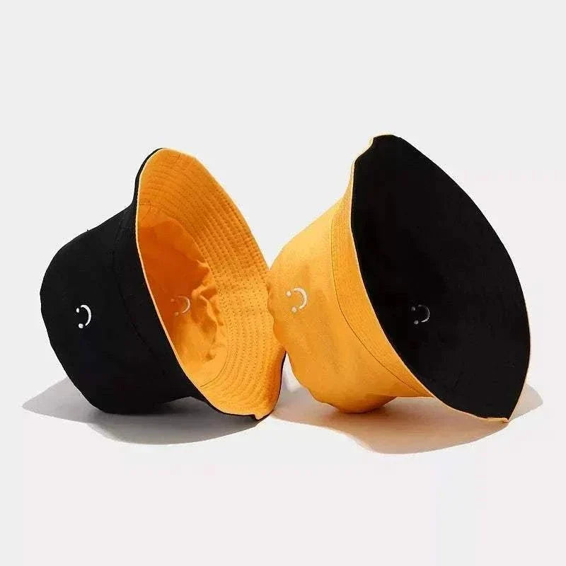 Women’s Smiley Face Bucket Hat in black and yellow cotton, shown as two hats with small embroidered smiley details