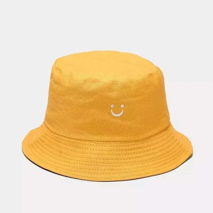 Women’s Smiley Face Bucket Hat in mustard yellow cotton with a small white embroidered smile and stitched brim