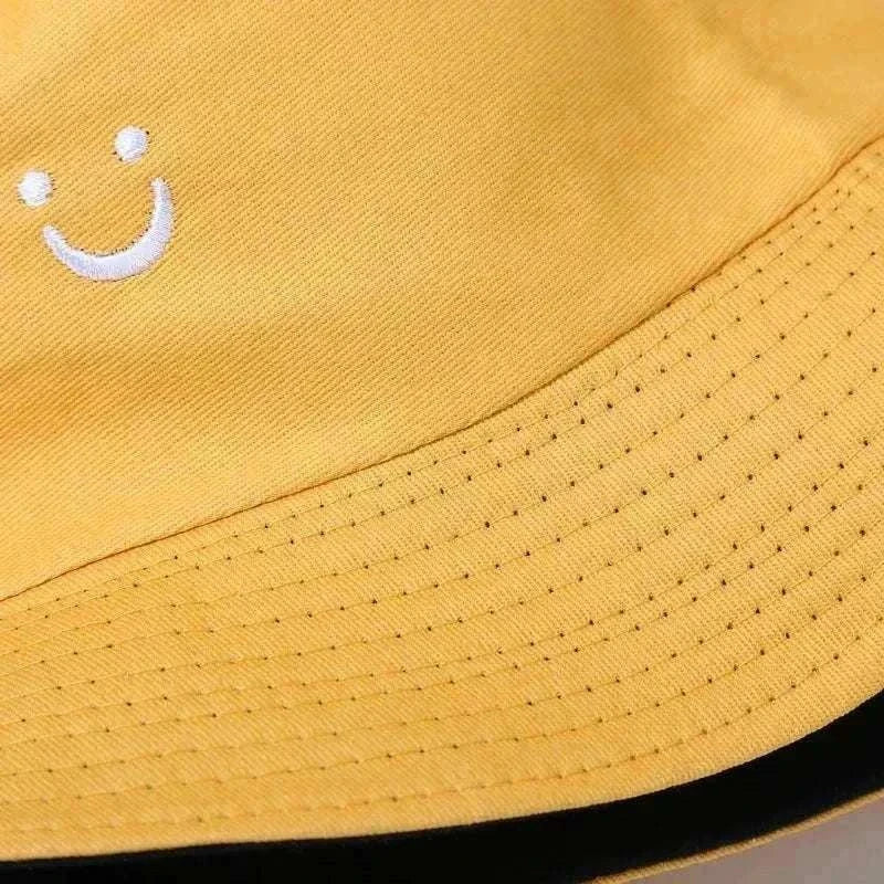 Women’s Smiley Face Bucket Hat in mustard yellow cotton with a small white embroidered smiley and stitched brim