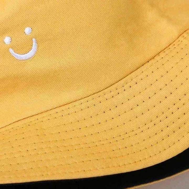 Women’s Smiley Face Bucket Hat in mustard yellow cotton with a small white embroidered smiley and stitched brim