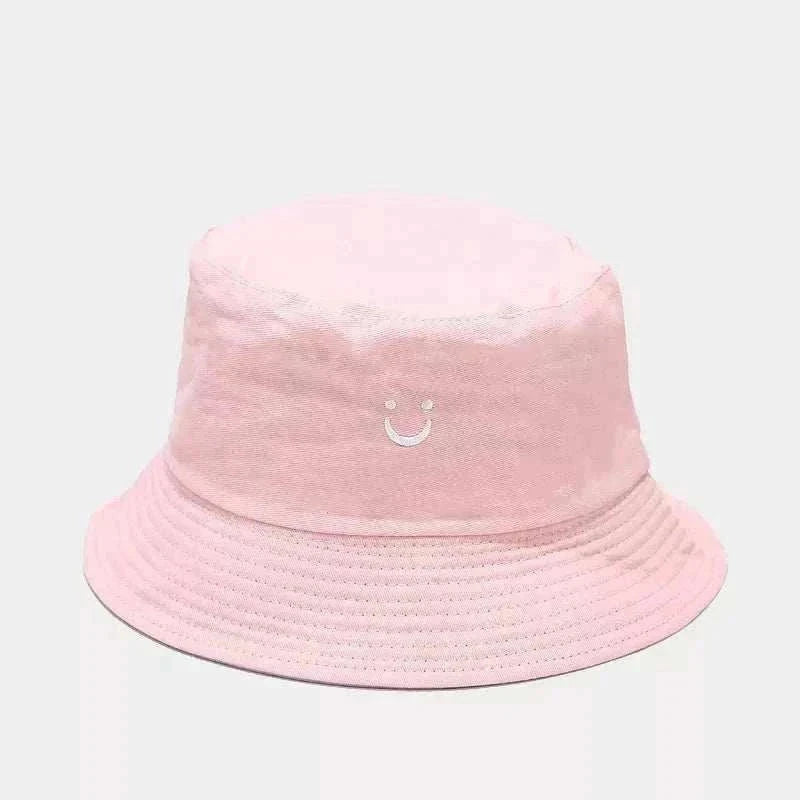 Women’s Smiley Face Bucket Hat in pale pink cotton with a small embroidered white smiley and stitched brim