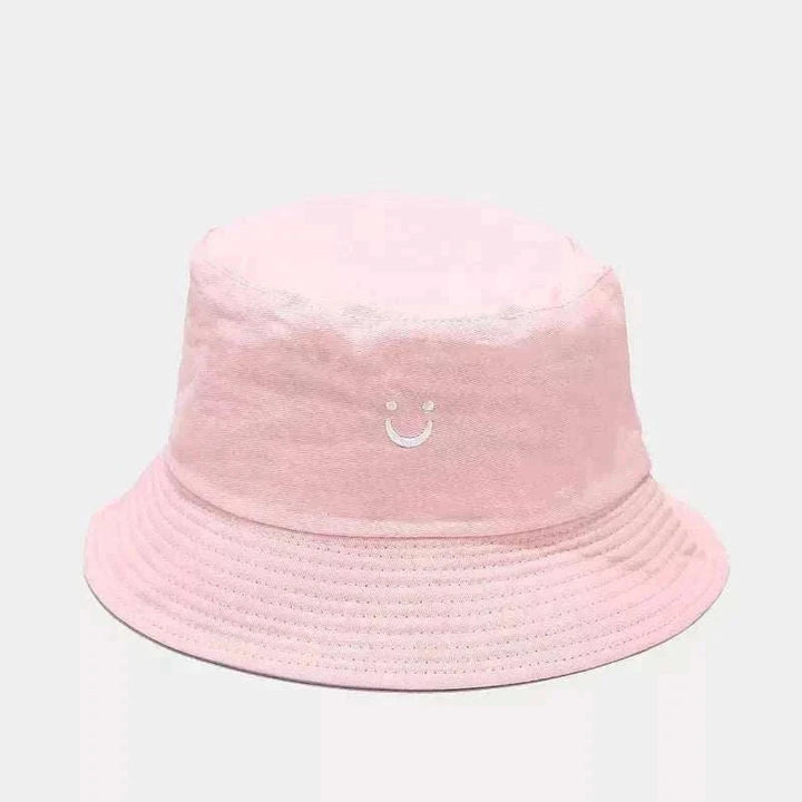 Women’s Smiley Face Bucket Hat in pale pink cotton with a small embroidered white smiley and stitched brim