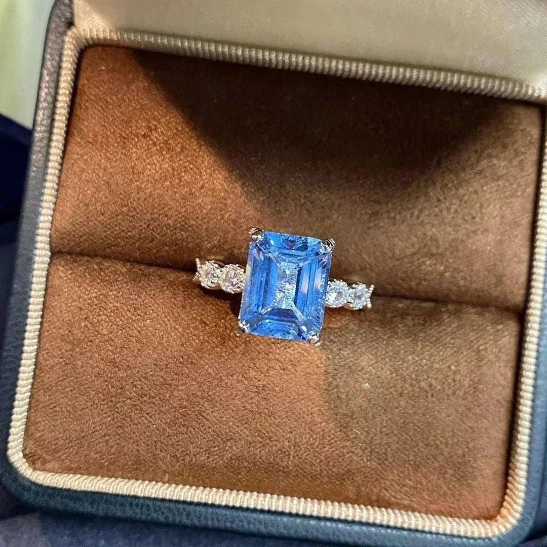 Women’s Zircon Statement Ring with a rectangular blue center stone, clear sparkling side stones, and a silver-tone band
