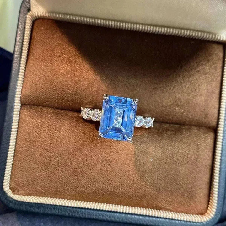 Women’s Zircon Statement Ring with a rectangular blue center stone, clear sparkling side stones, and a silver-tone band
