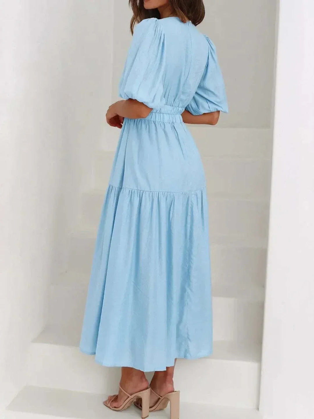 Woman wearing a V-neck puff sleeve midi dress from Hot Topic Goods in a casual outdoor setting