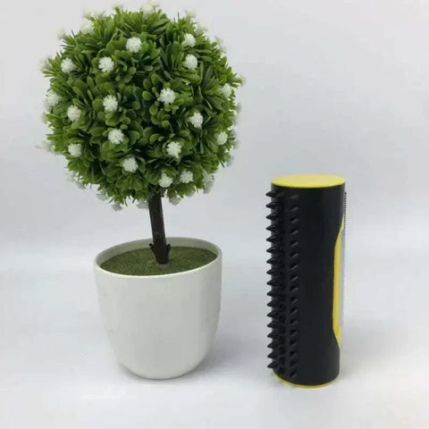 Pet Hair Remover Brush with durable stainless steel teeth, compact and lightweight design, next to a small potted plant.