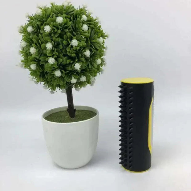 Pet Hair Remover Brush with durable stainless steel teeth, compact and lightweight design, next to a small potted plant.