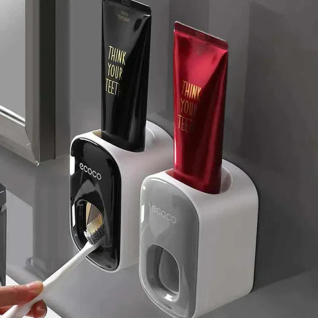 Automatic toothpaste dispenser with toothbrush holder mounted on a bathroom wall.