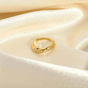 Gold snake-shape ring with zircon stones on cream satin background.